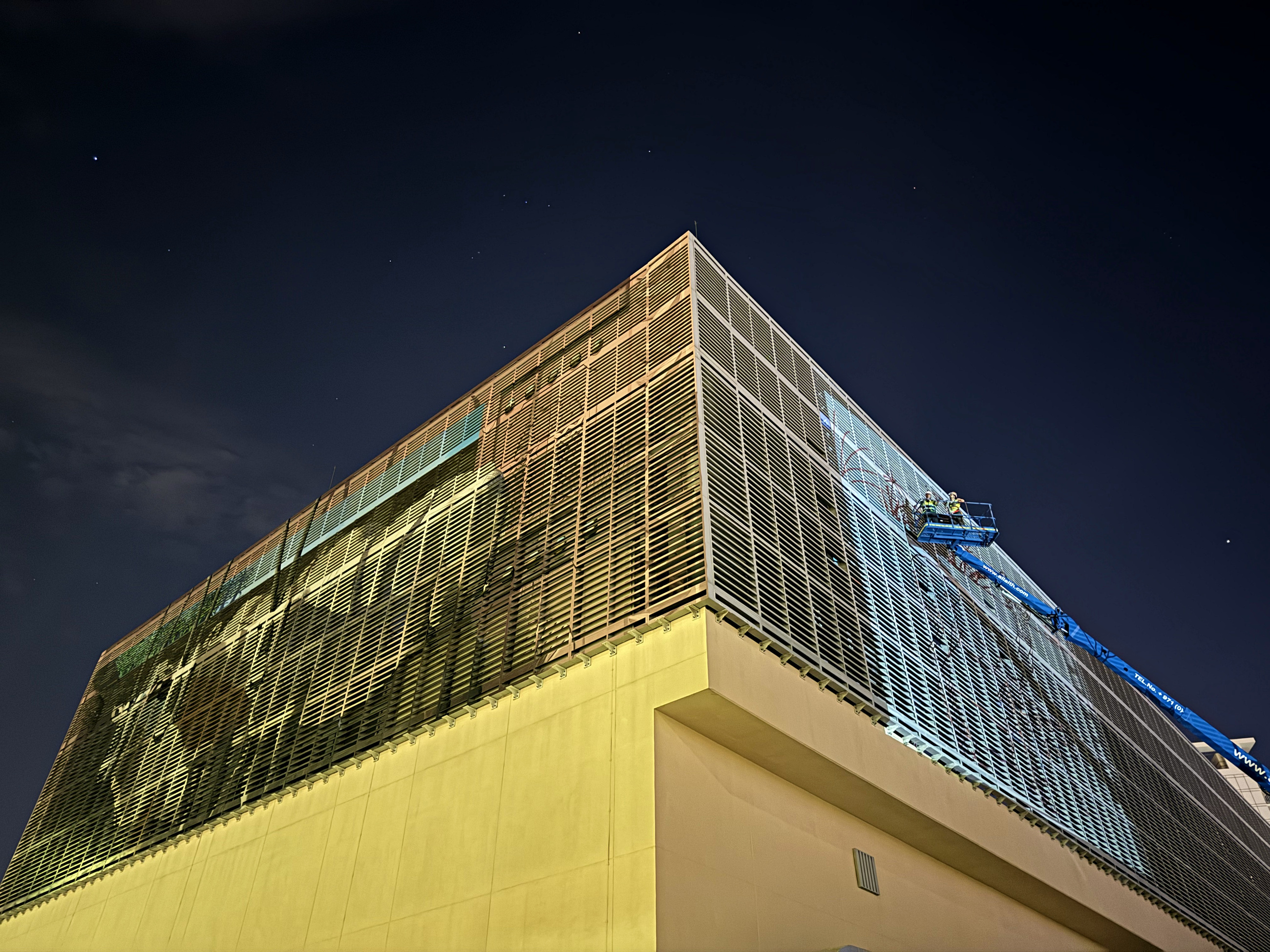 Specialist mural crew working at height across the Tabreed Al Maryah facade at night